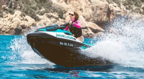 Woman riding a Sea-Doo jet ski during a jet ski tour with jetski.club in Ibiza Mediterranean waters near rocky coastline