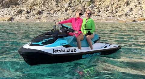 Two women riding a jet ski in the crystal clear waters of Ibiza during a jetski.club tour exploring hidden coves and secret spots along the coastline.