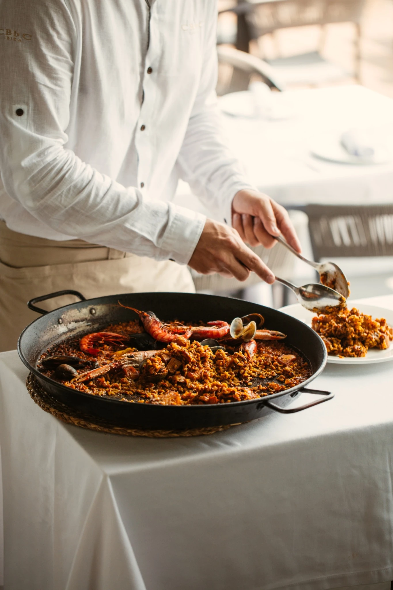 Chef serving seafood paella at CBBC Marina Santa Eulalia restaurant in Ibiza