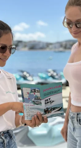 Guests reviewing jet ski tour flyer at jetski.club reception with jet skis in the background