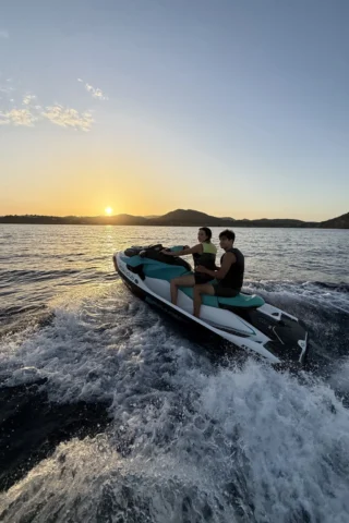 Couple enjoying a Sunset Jet-Ski Tour in Ibiza with Ibiza Island and the sunset in the background