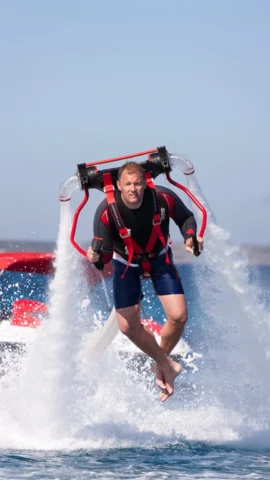 Lindsay McQueen flying a water-propelled jetpack connected to a SEA-DOO jet boat from Yacht Watersports Ibiza during a luxury yacht watersports experience in Ibiza.